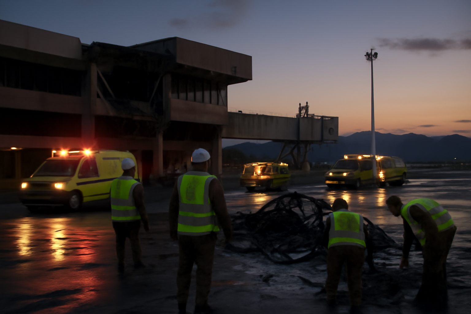 Damaged perimeter fencing and emergency vehicles near a regional airport terminal in southern Saudi Arabia