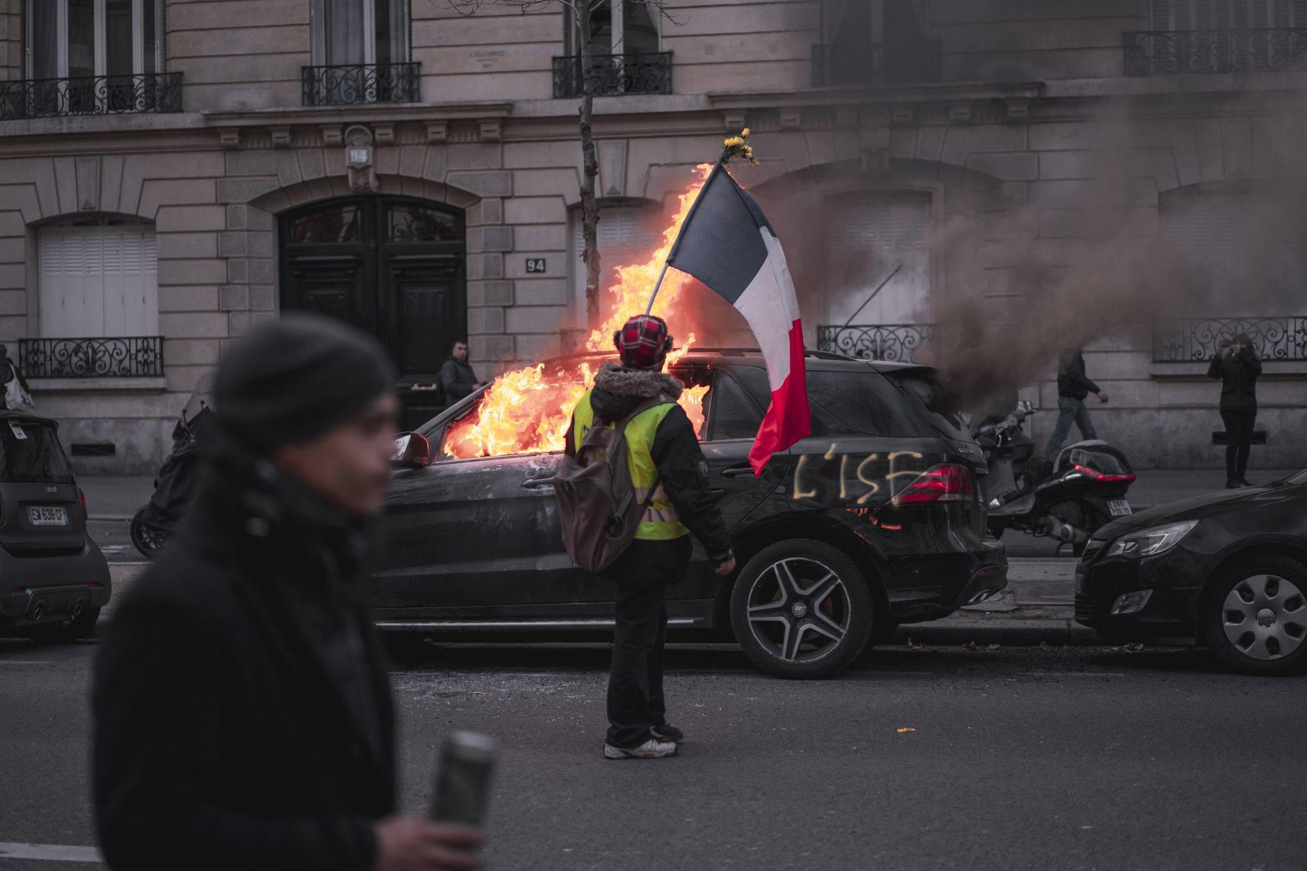Riot police in protective gear stand near tear gas smoke on a Paris street during a demonstration