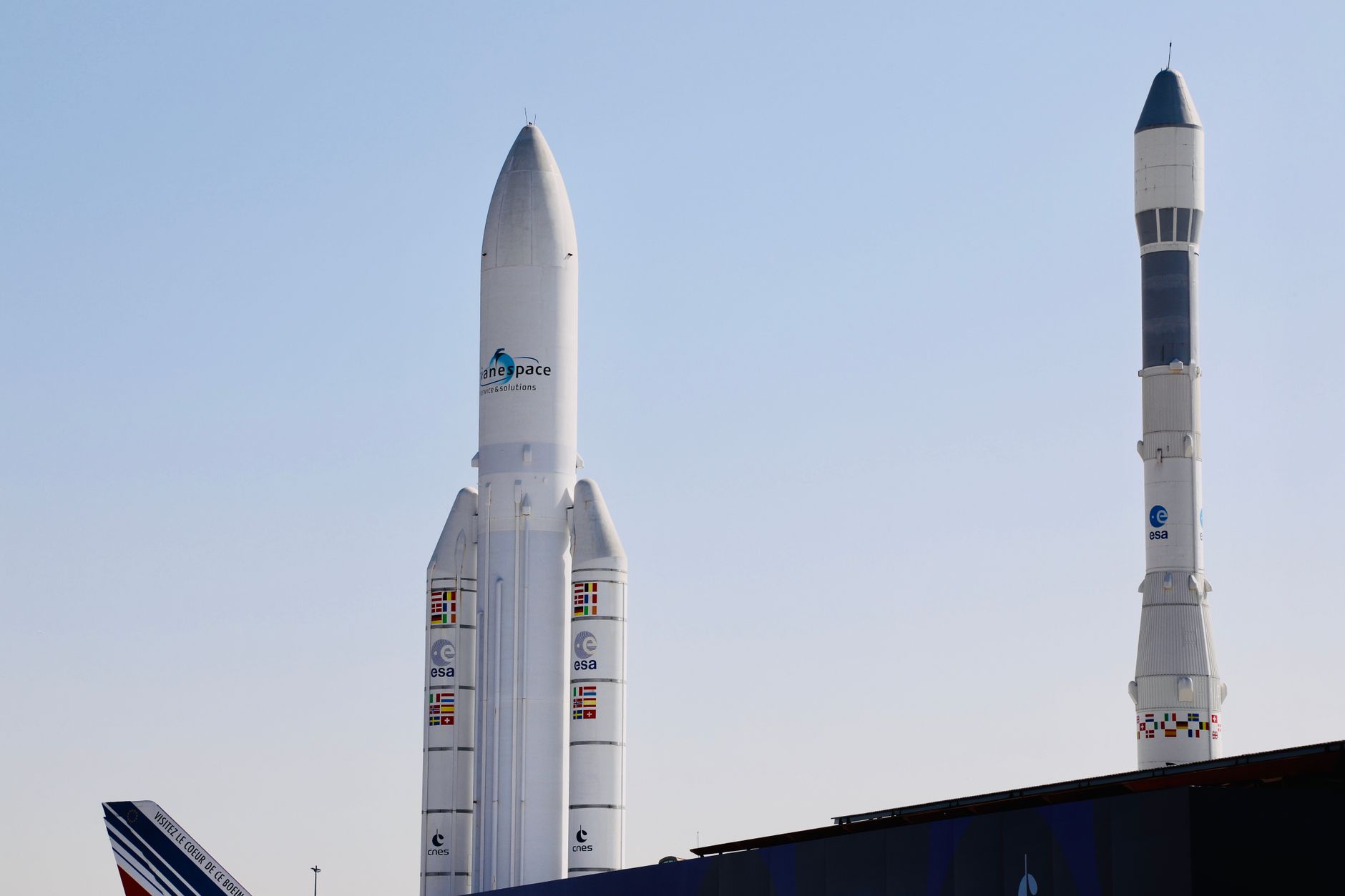 A rocket lifts off from a coastal launch pad under a clear sky
