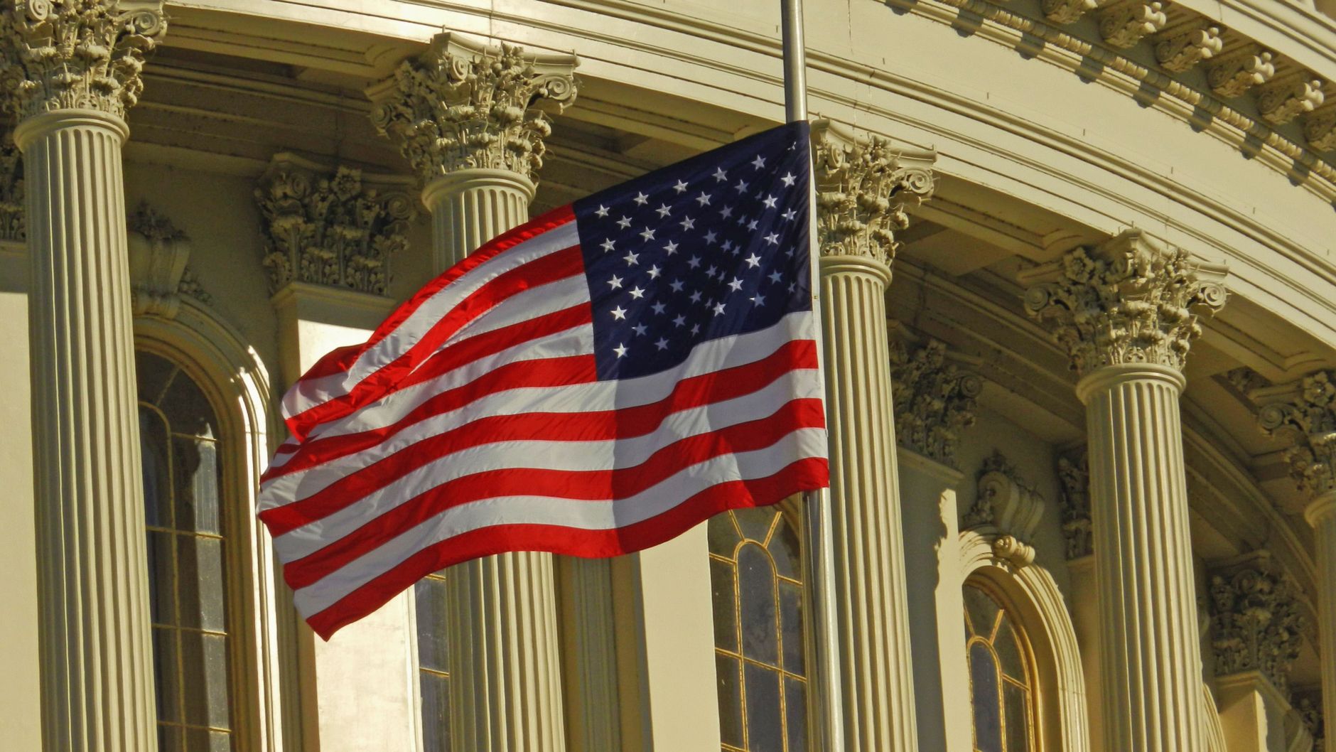 Exterior of a federal courthouse with an American flag under overcast sky