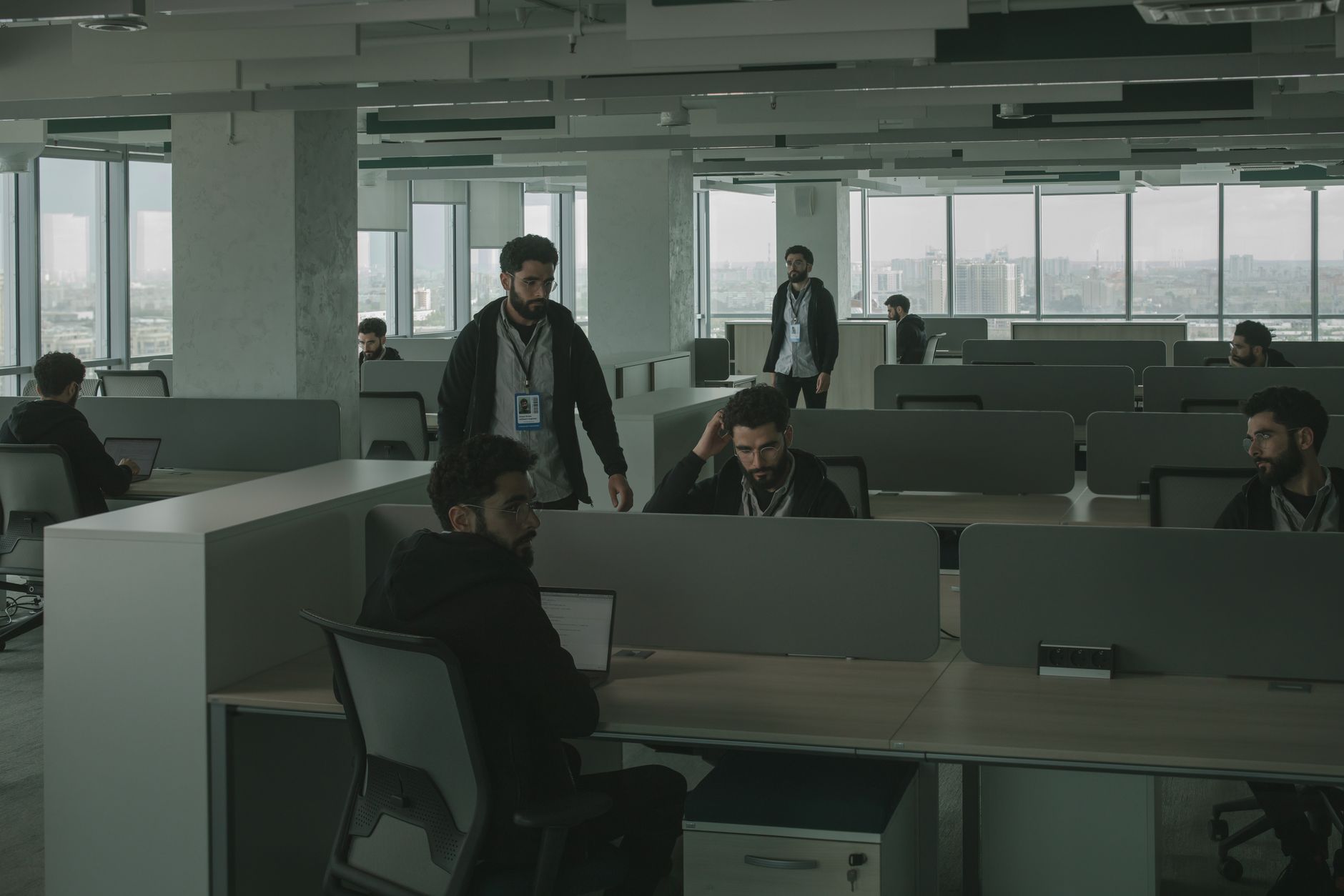 Rows of enterprise office monitors displaying a generic AI chat interface during a workday