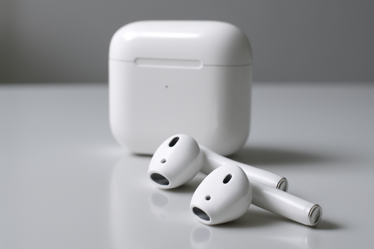 White wireless earbuds and charging case resting on a reflective surface