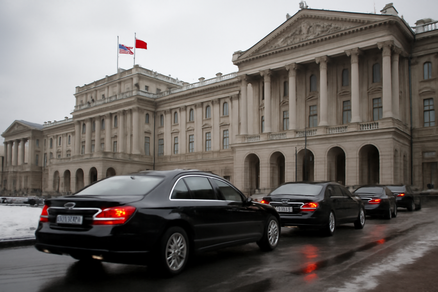 Diplomatic motorcade arriving at a government building in St Petersburg under an overcast sky