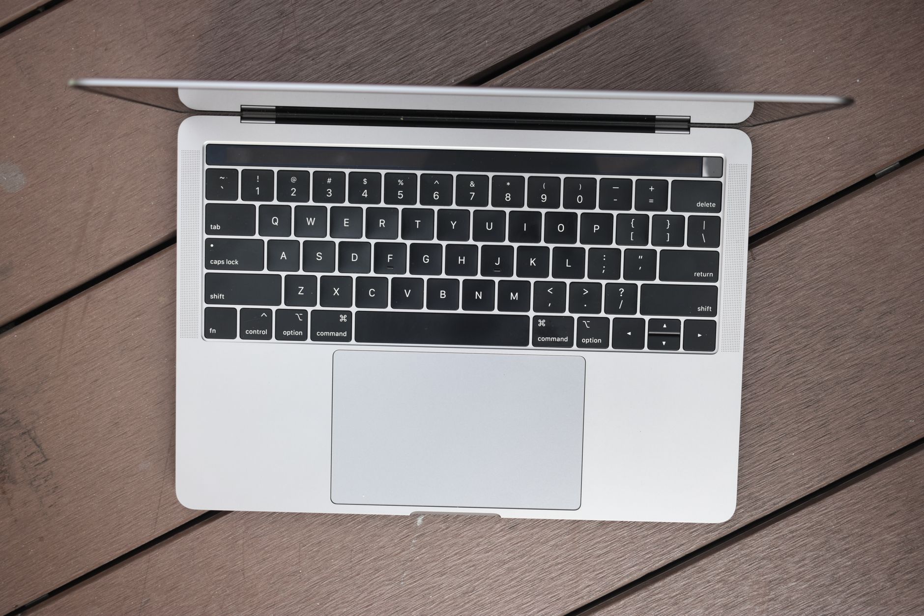 Bright MacBook Pro touchscreen display showing vivid colors against deep black background on a desk