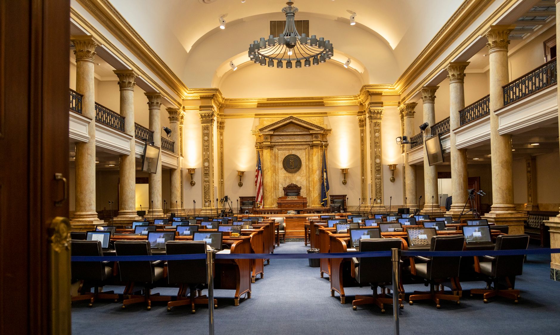 Empty Senate chamber desks lit by afternoon light with a wall map in the background