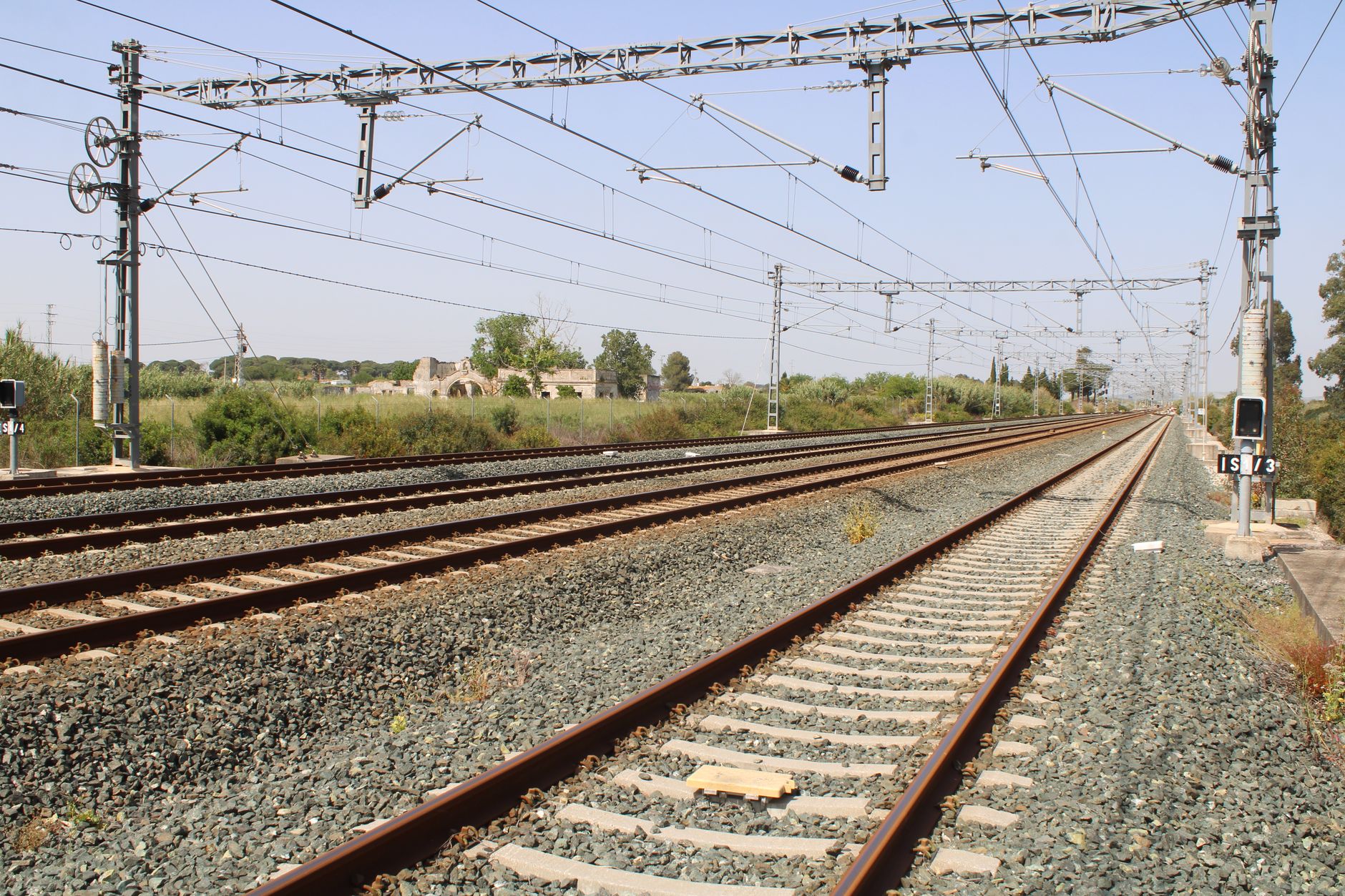 Spanish passenger train tracks with emergency lights in the distance at dusk