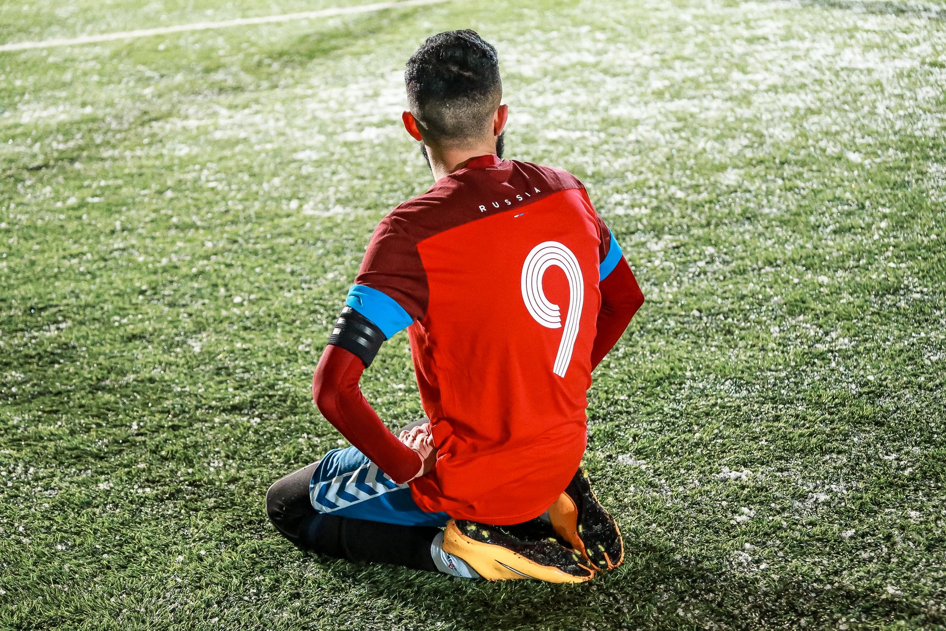 Soccer striker in a club away kit lifting a crystal trophy on a stadium pitch