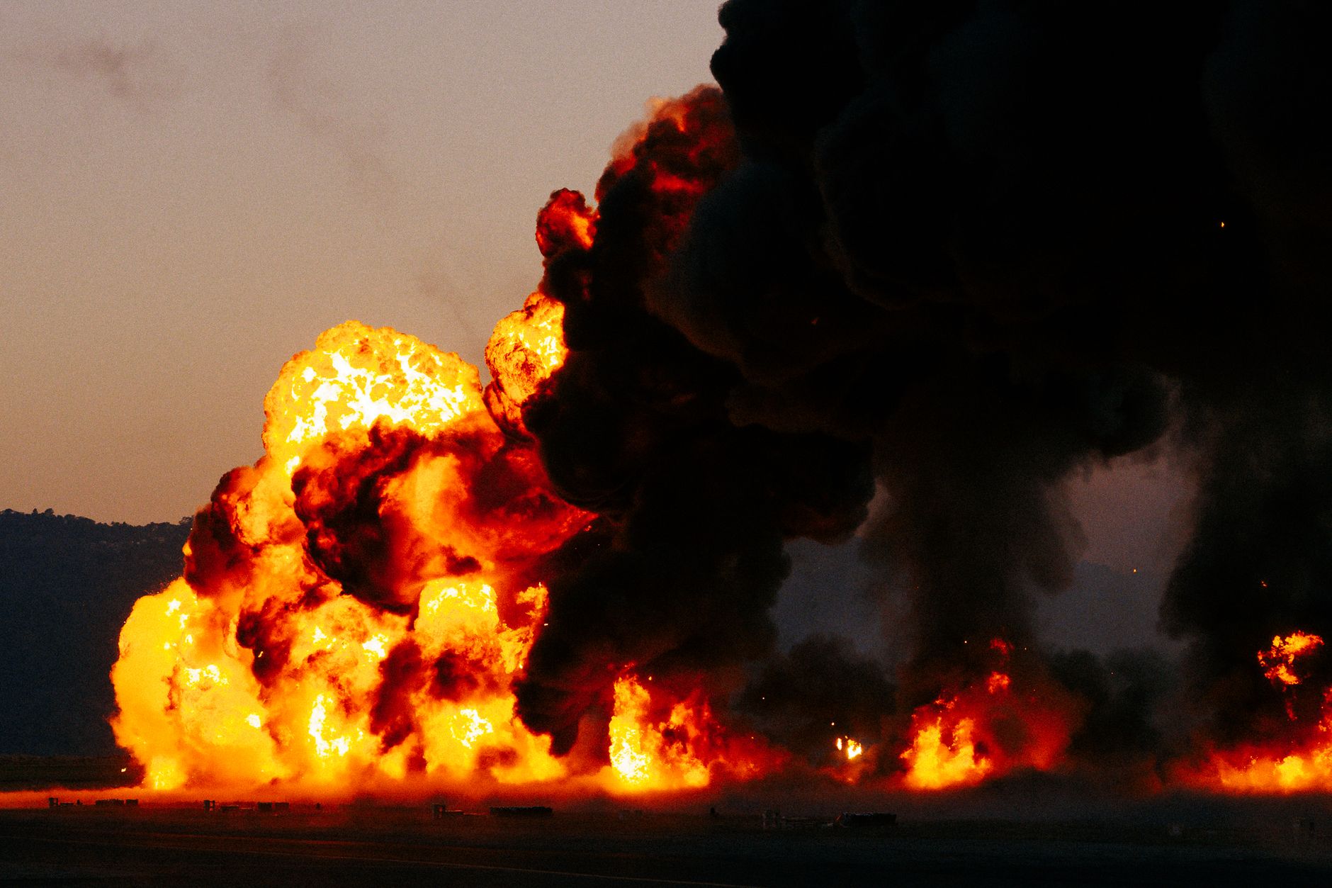 Firefighters extinguish a burned car near a freeway pillar close to LAX at dawn