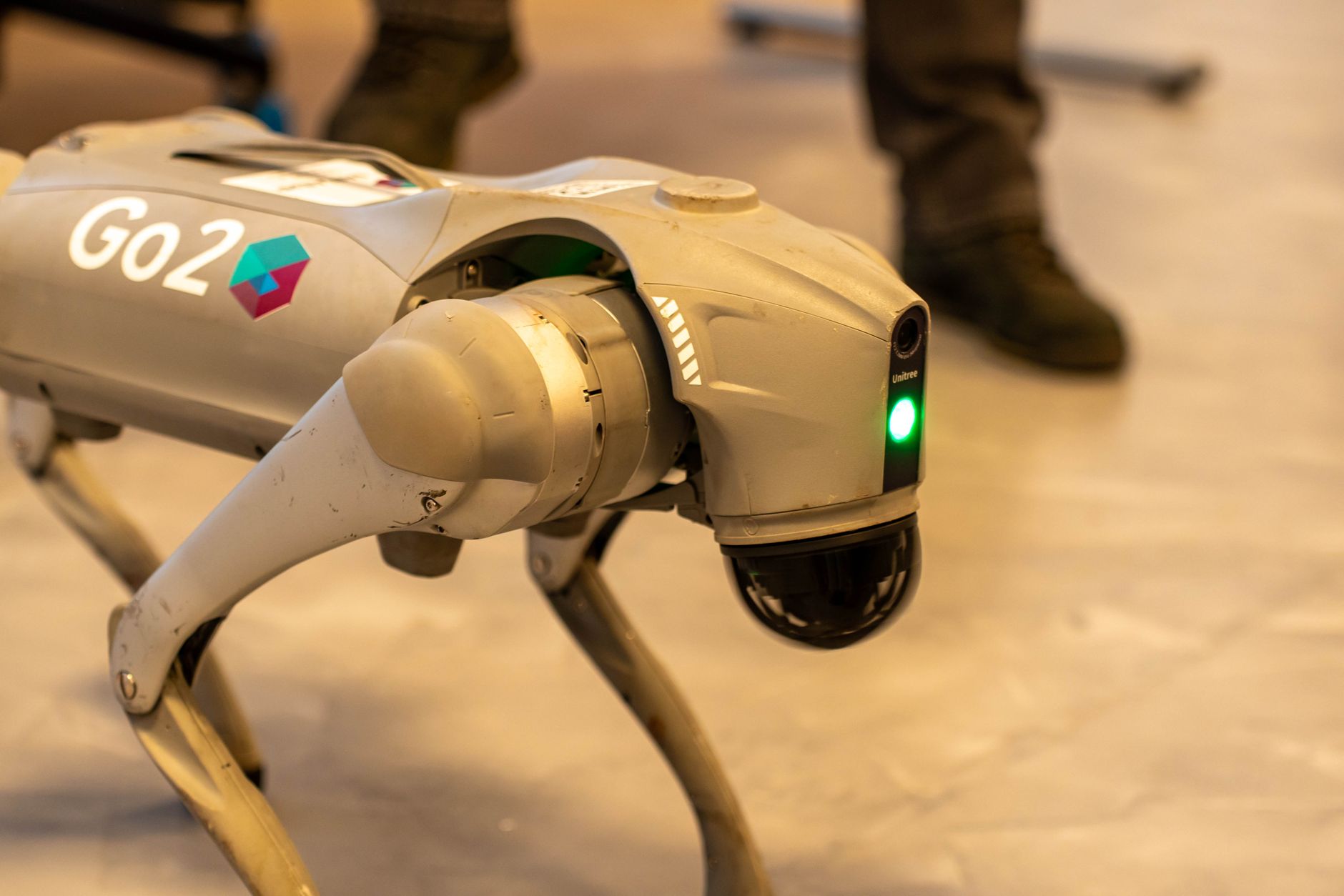 A quadruped robot dog equipped with sensors and a camera mast standing near a tunnel entrance