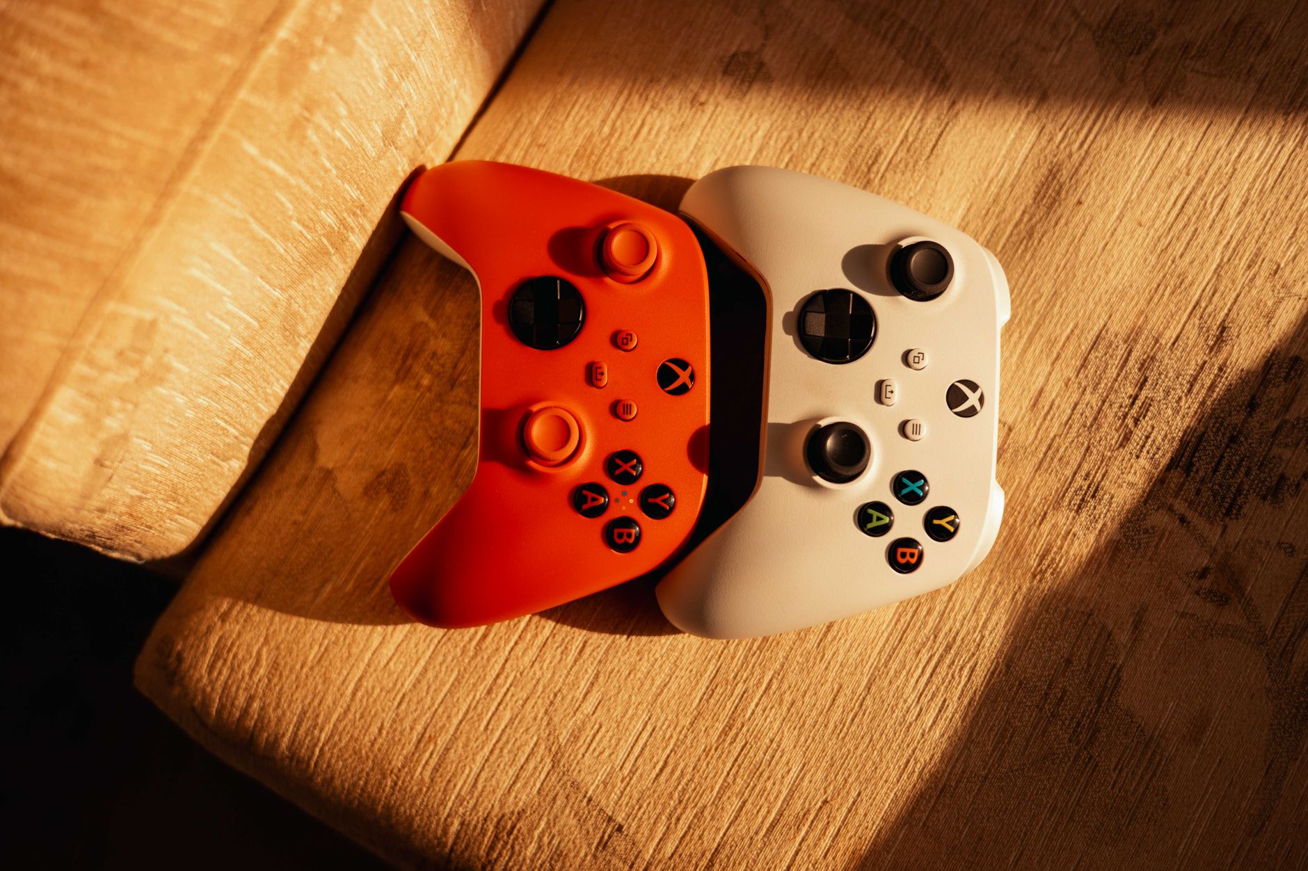 Xbox console and controller sitting on a desk in front of a dimly lit office window