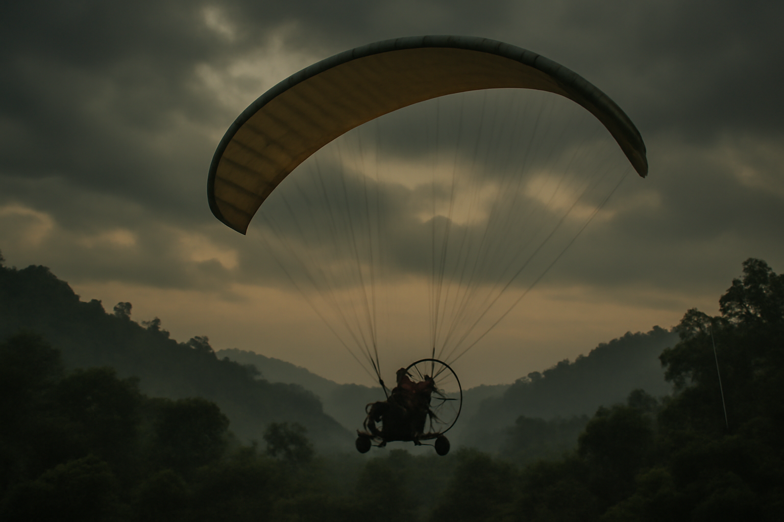 A small motorized paraglider aircraft flying low over green hills at dusk