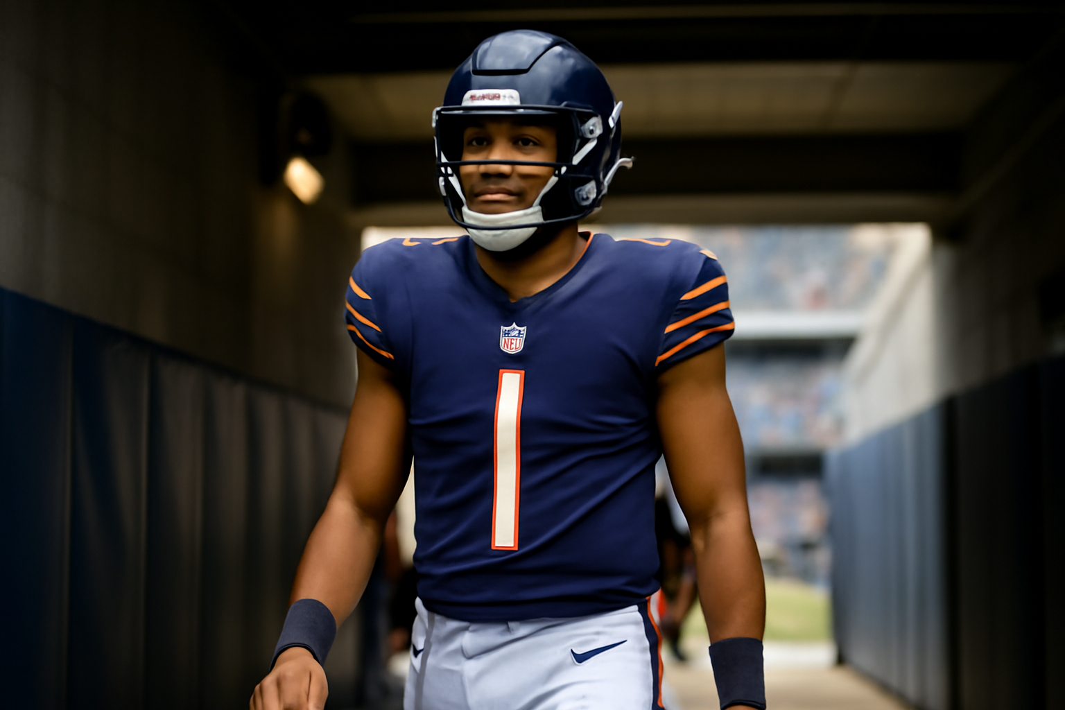 Chicago Bears quarterback walking through a stadium tunnel in a home jersey before a game