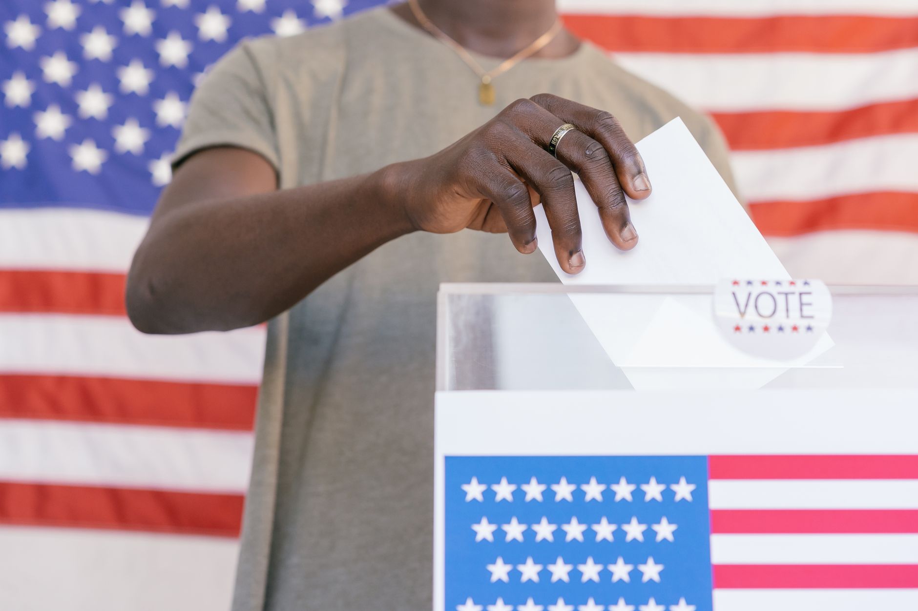 A voter drops a ballot into a drop box outside a polling location on a cloudy afternoon