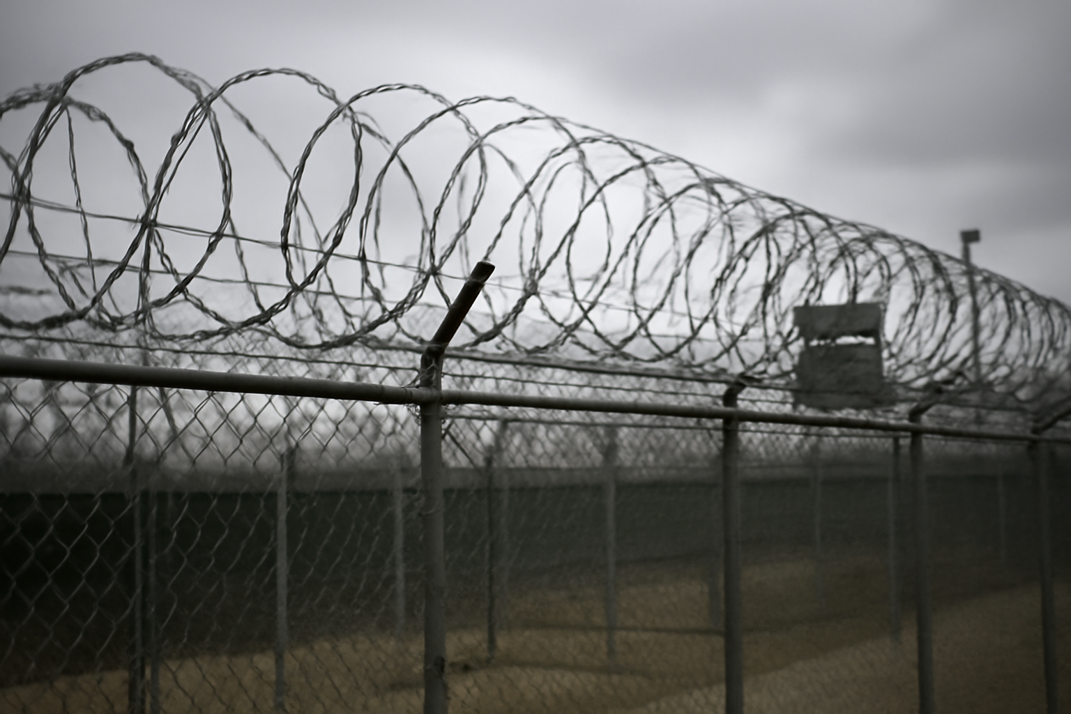 Razor wire fencing outside a prisoner detention facility under overcast sky