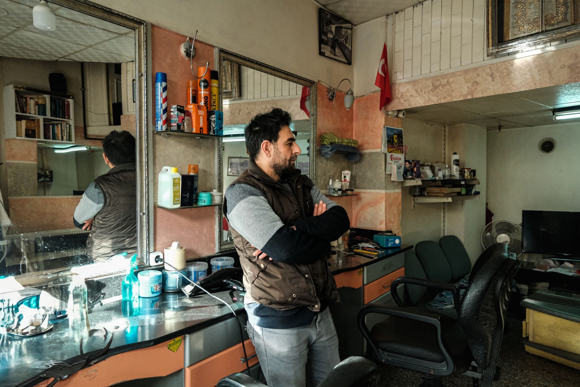 A hairdresser blow-drying a client's hair inside a small high-street salon