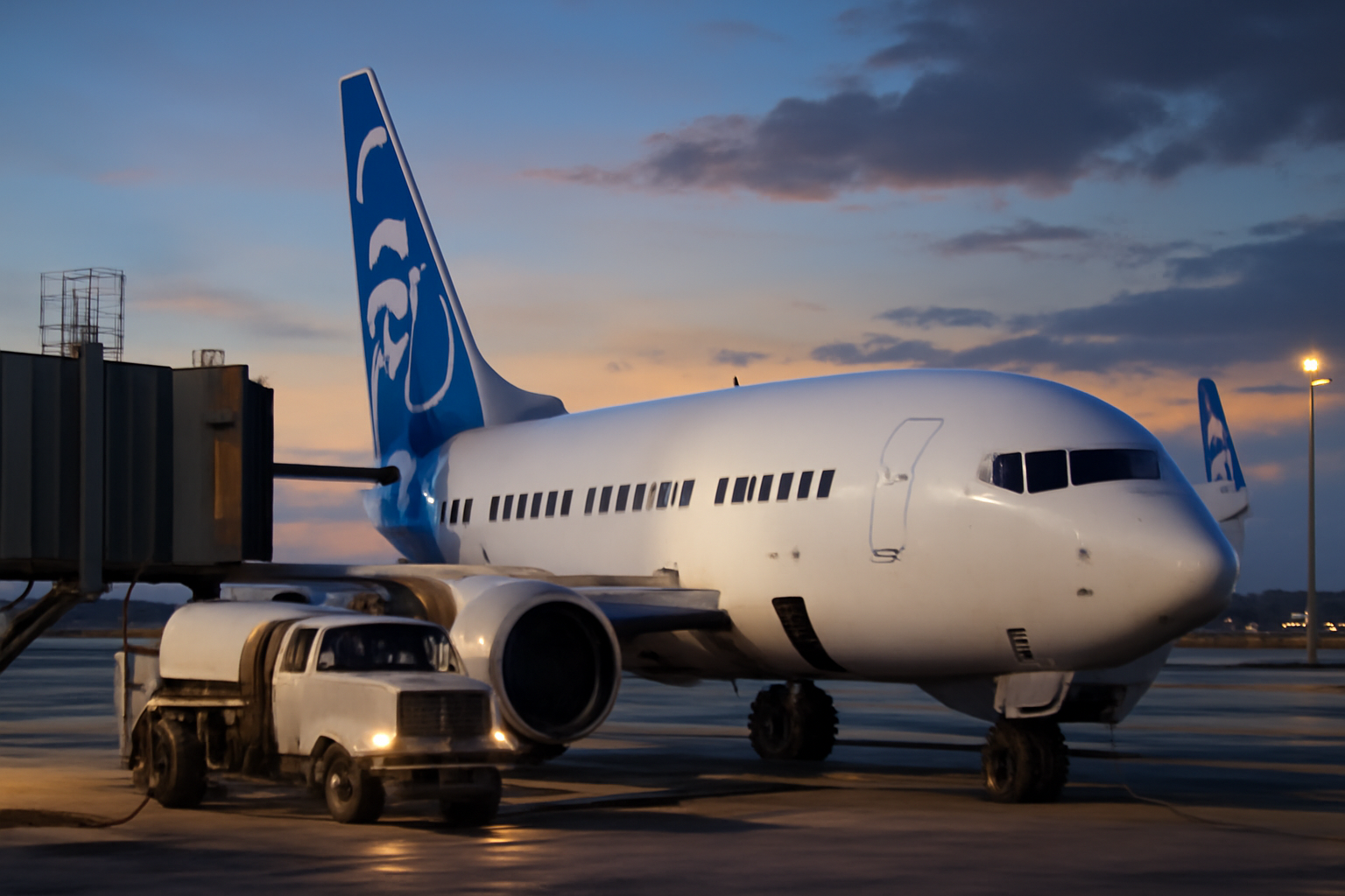 Alaska Airlines aircraft at a gate with a newly designed premium cabin seat visible through the jet bridge window