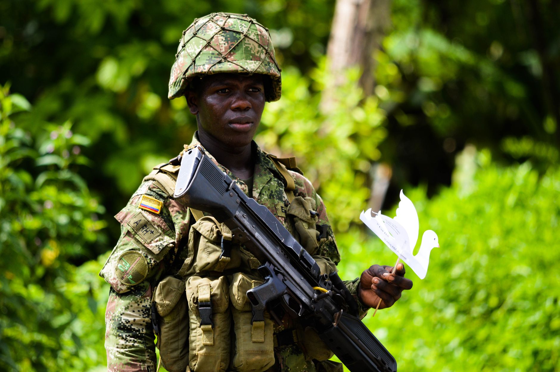 Colombian army soldiers on patrol near a rural checkpoint under overcast sky