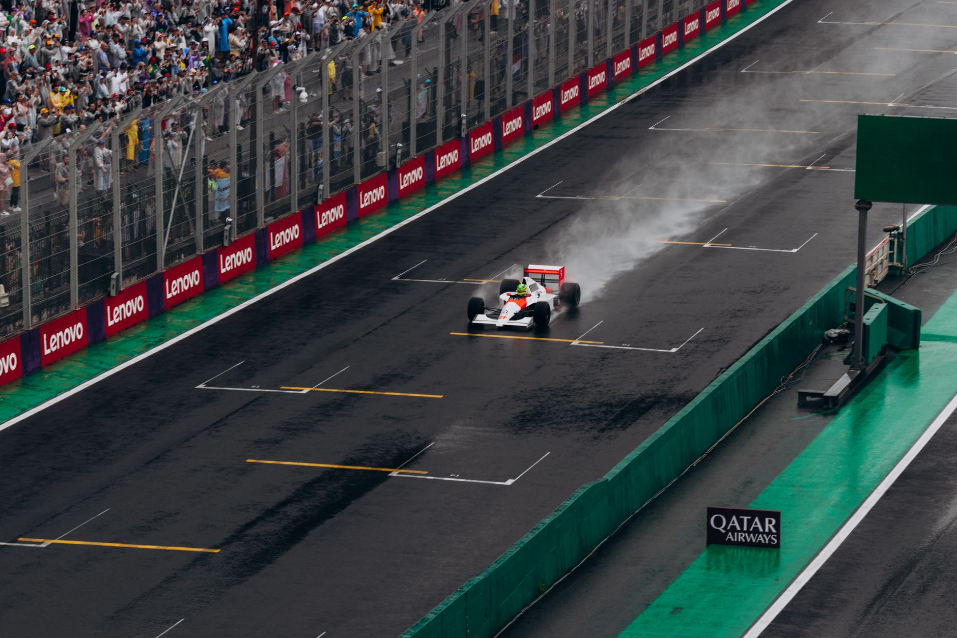 Formula One driver in racing suit standing beside car on pit lane during a race weekend