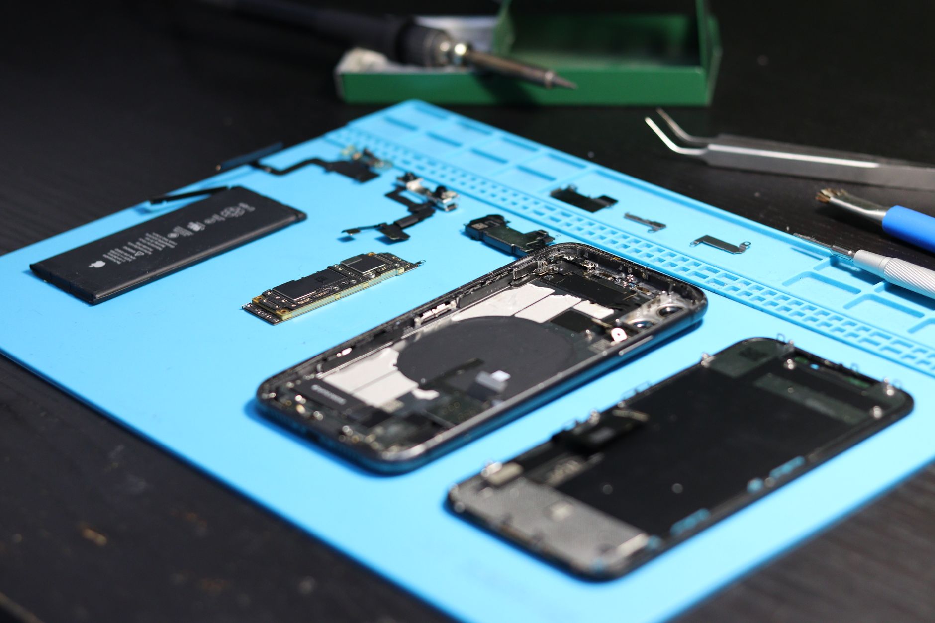 Disassembled foldable smartphone showing exposed hinge and inner OLED display during a repair teardown