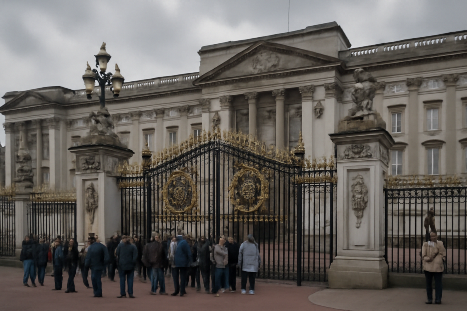 Exterior of Buckingham Palace gates with tourists in the foreground on an overcast day