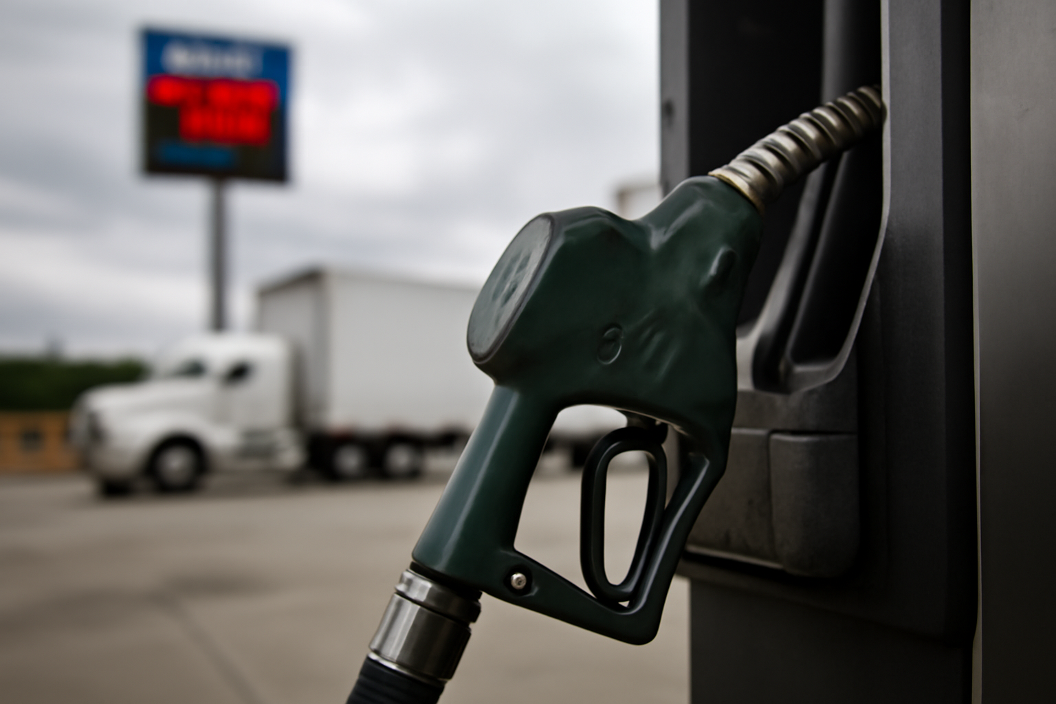 Diesel fuel pump nozzle at a US highway truck stop with price sign in background