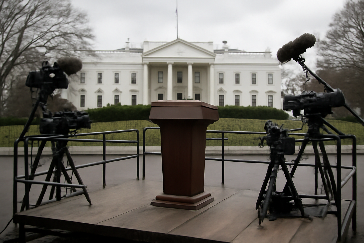 White House press pool cameras and microphones sit unused near a podium during a presidential event