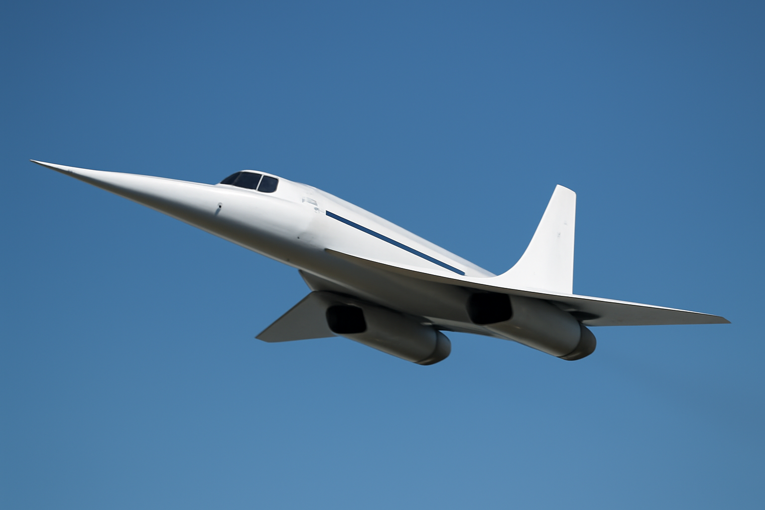 Elongated white experimental jet with a needle-thin nose flying against a clear blue sky