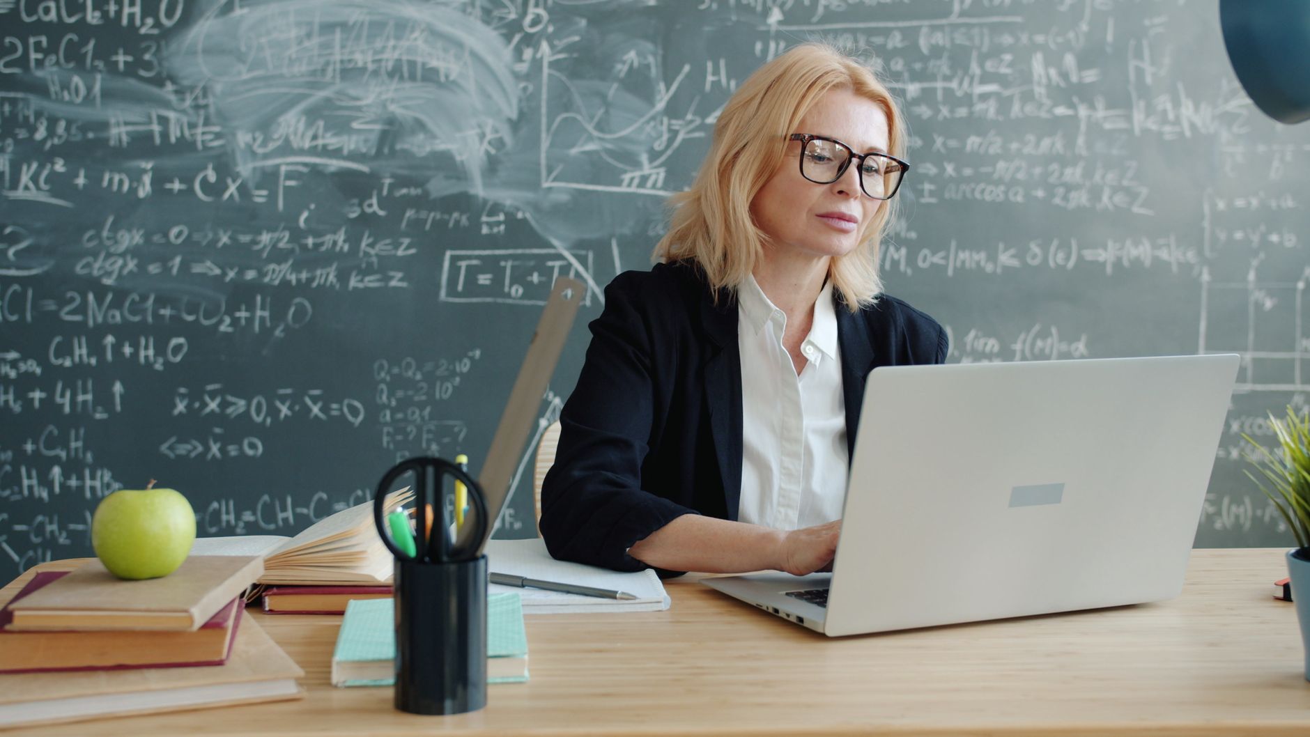 A special education classroom with a teacher kneeling beside a student's desk