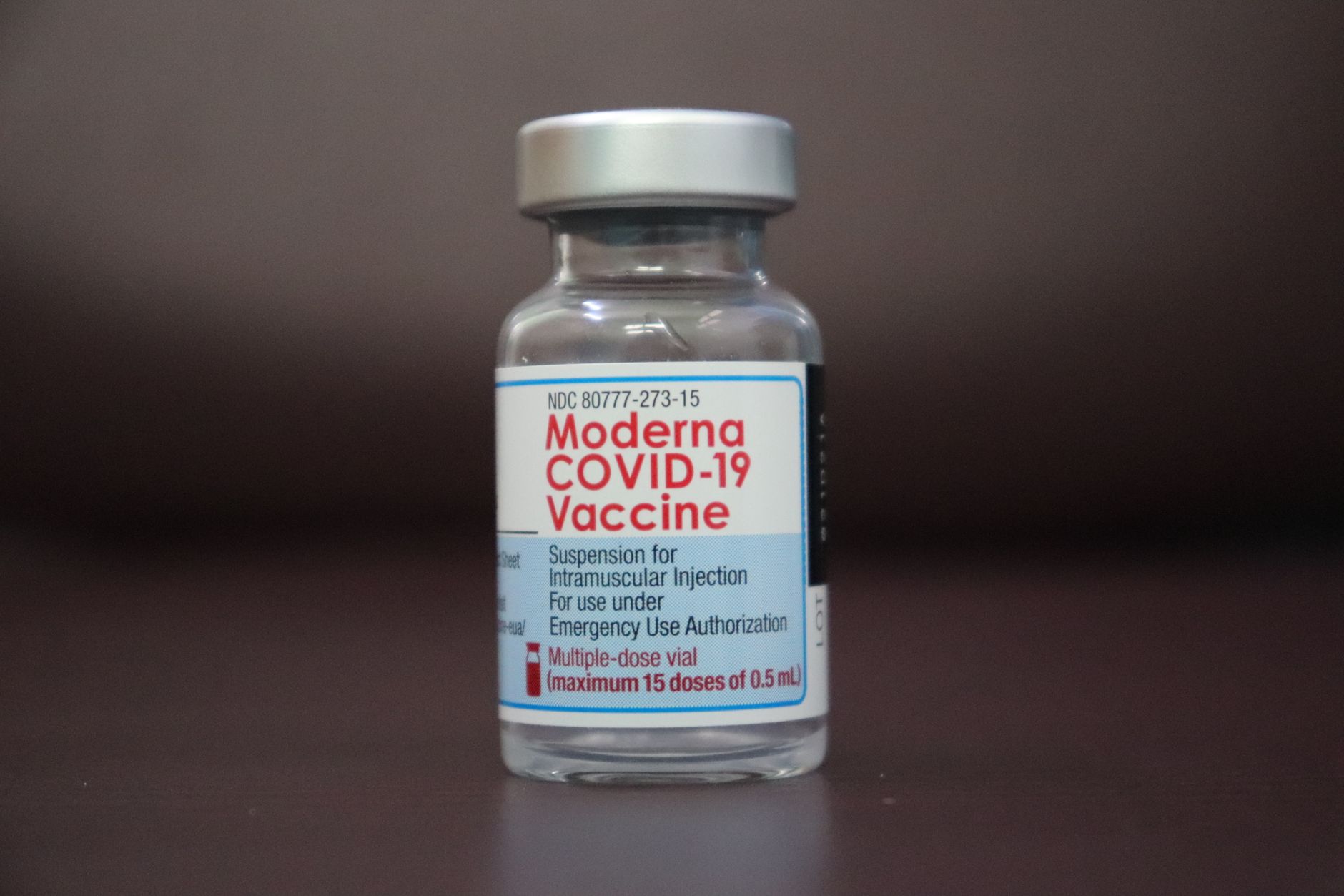 Vials of personalized mRNA vaccine doses on a laboratory tray beside a researcher's gloved hands