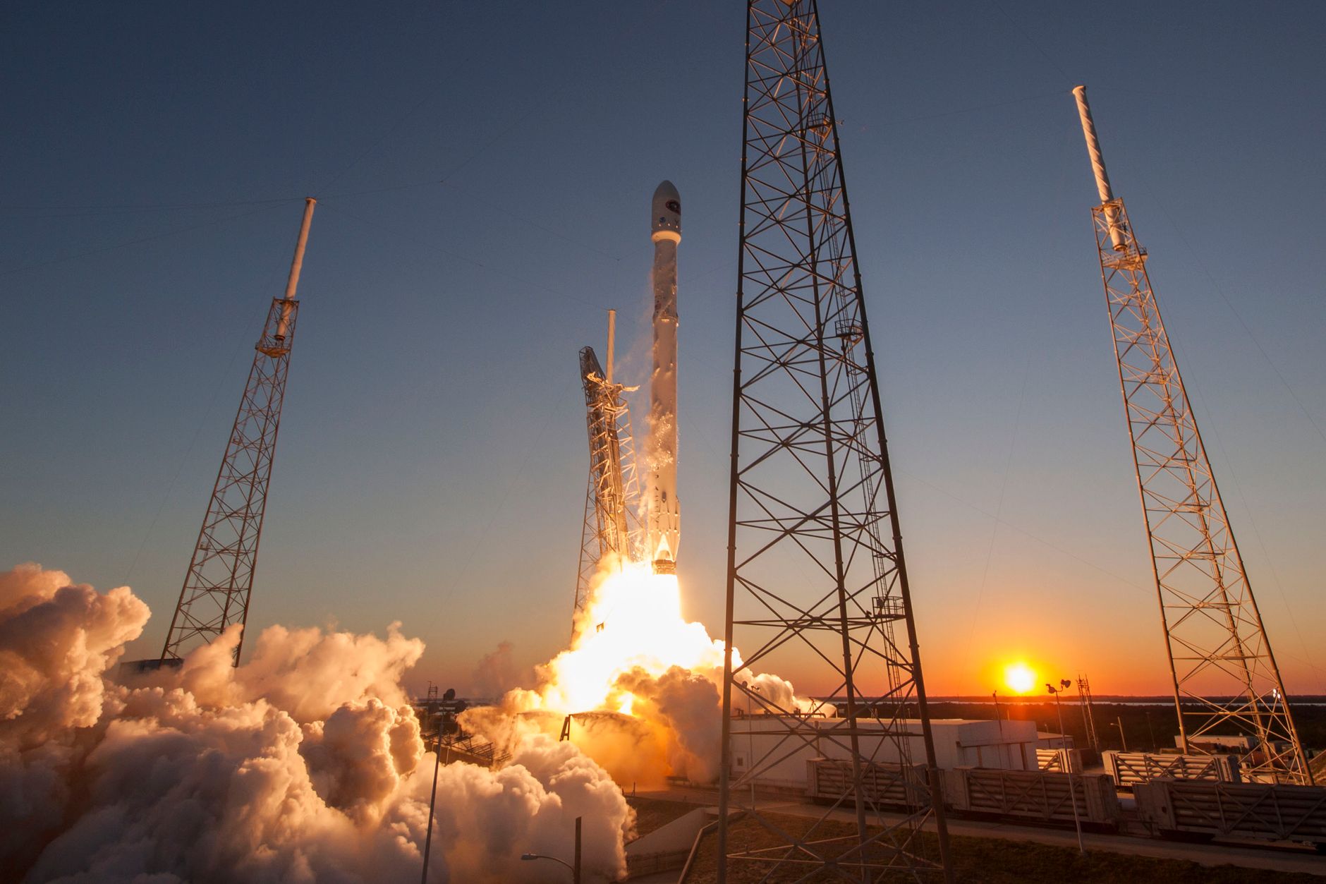 SpaceX rocket on a launch pad at dusk with the company logo visible on the fuselage