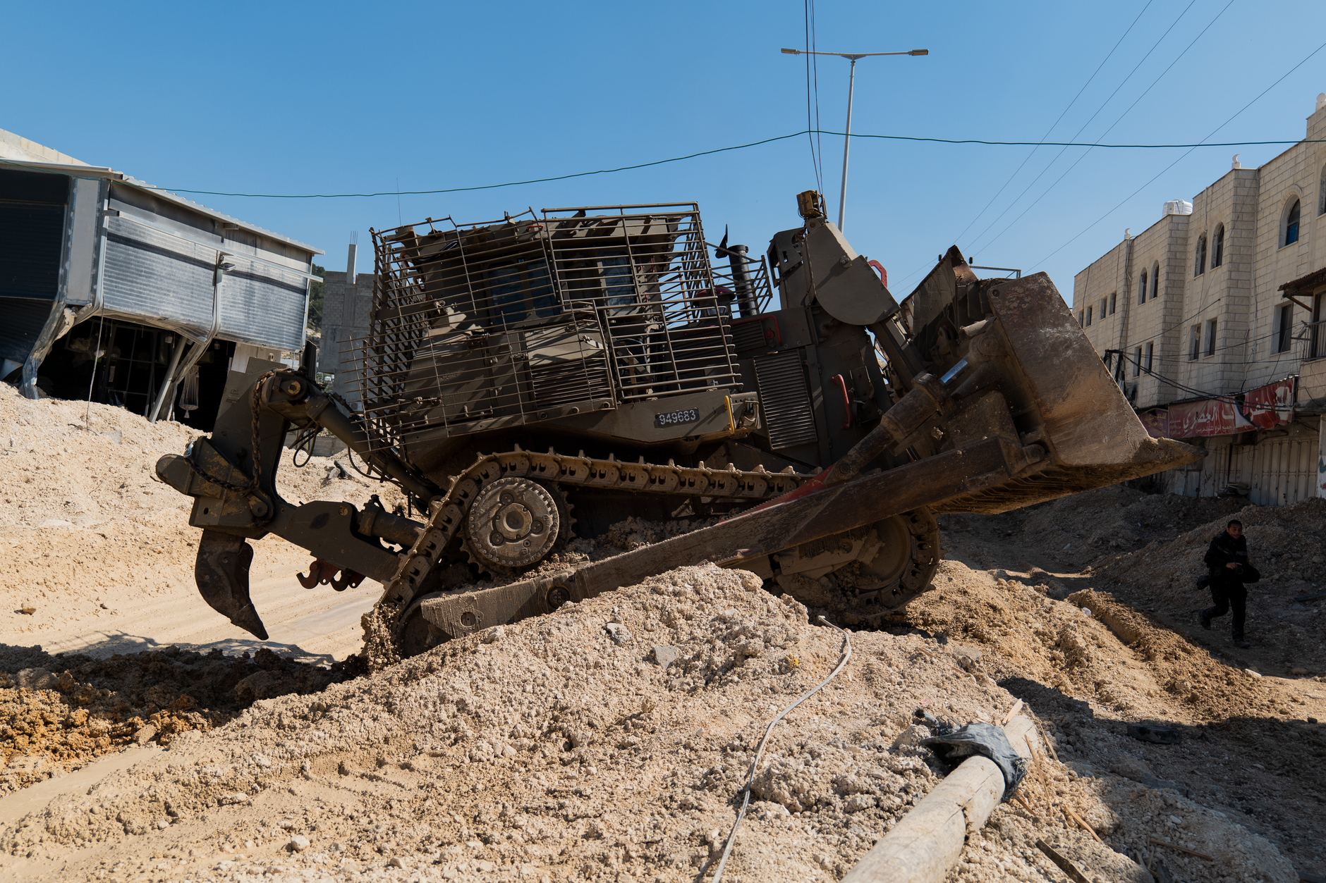 Bulldozer clearing rubble on a residential street in Hebron after a demolition operation