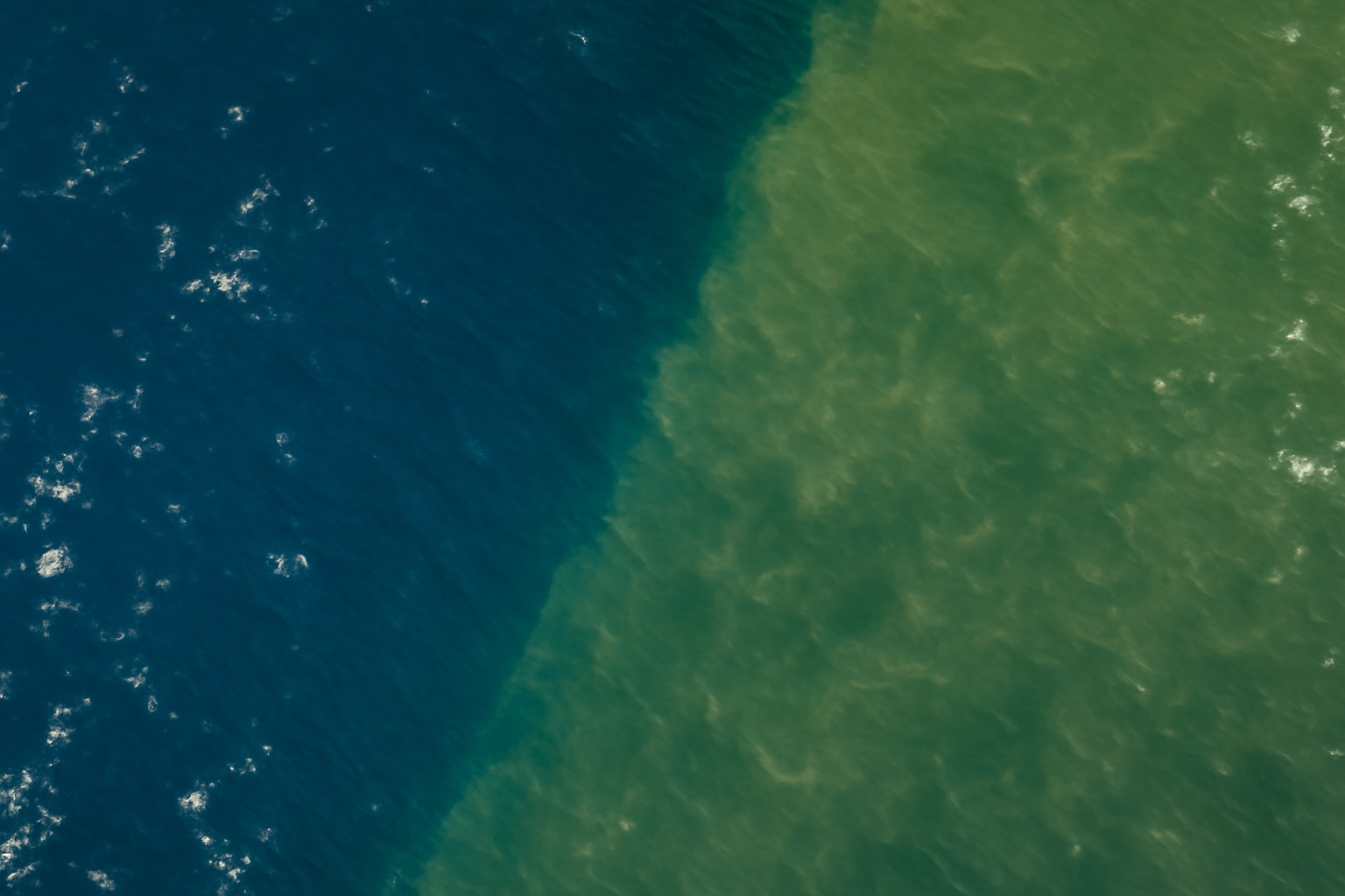 Satellite view of the equatorial Pacific Ocean shifting from green to deep blue water