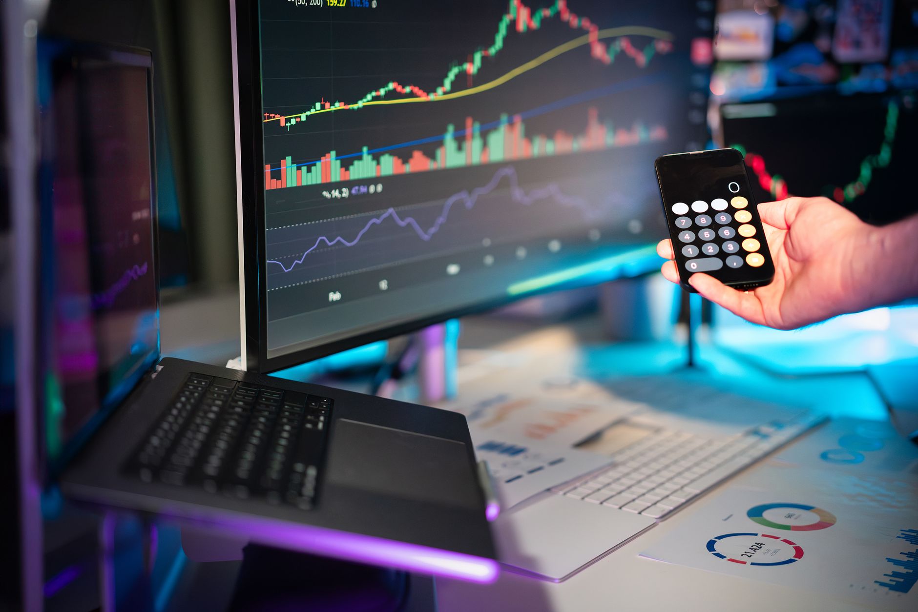 Darkened financial trading floor with red downward stock charts projected on large screens