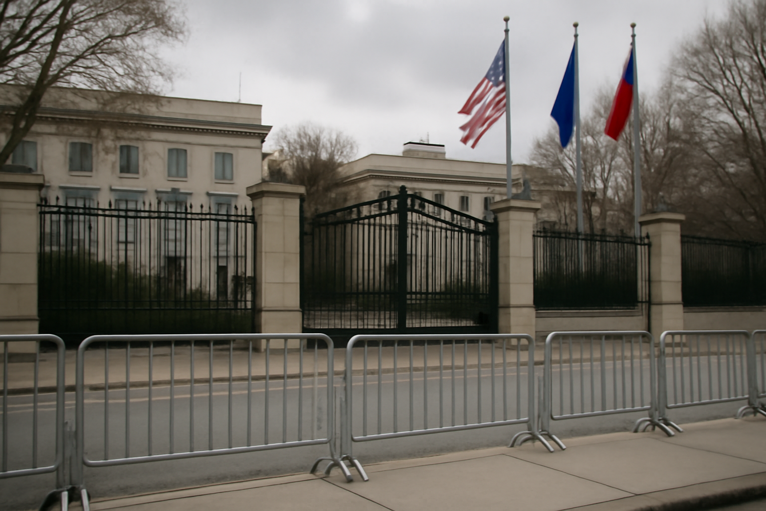 Security barriers and a closed gate outside a government embassy building under overcast sky
