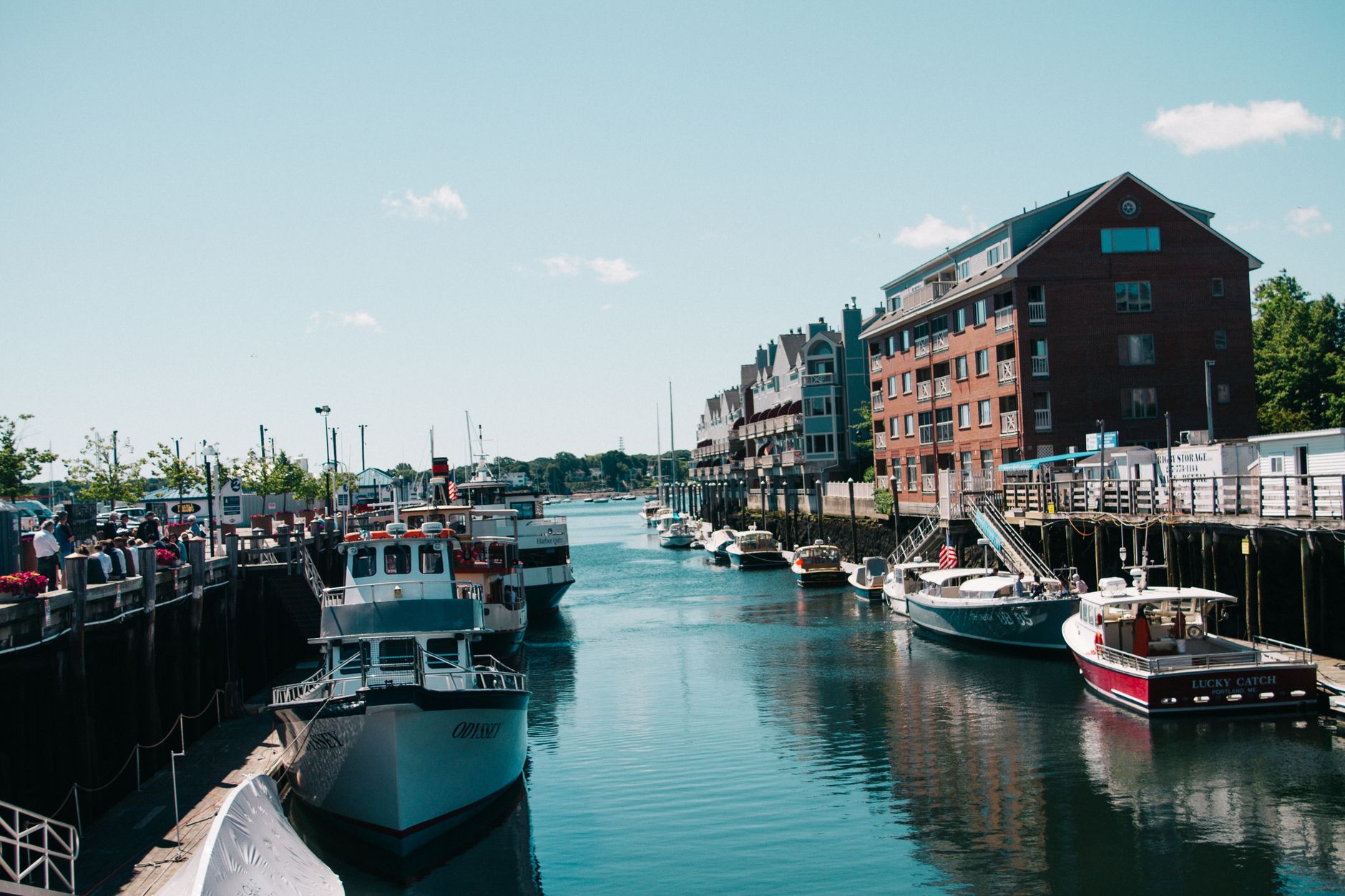 A lobster boat docked at a wooden wharf in Portland, Maine, with traps stacked on deck