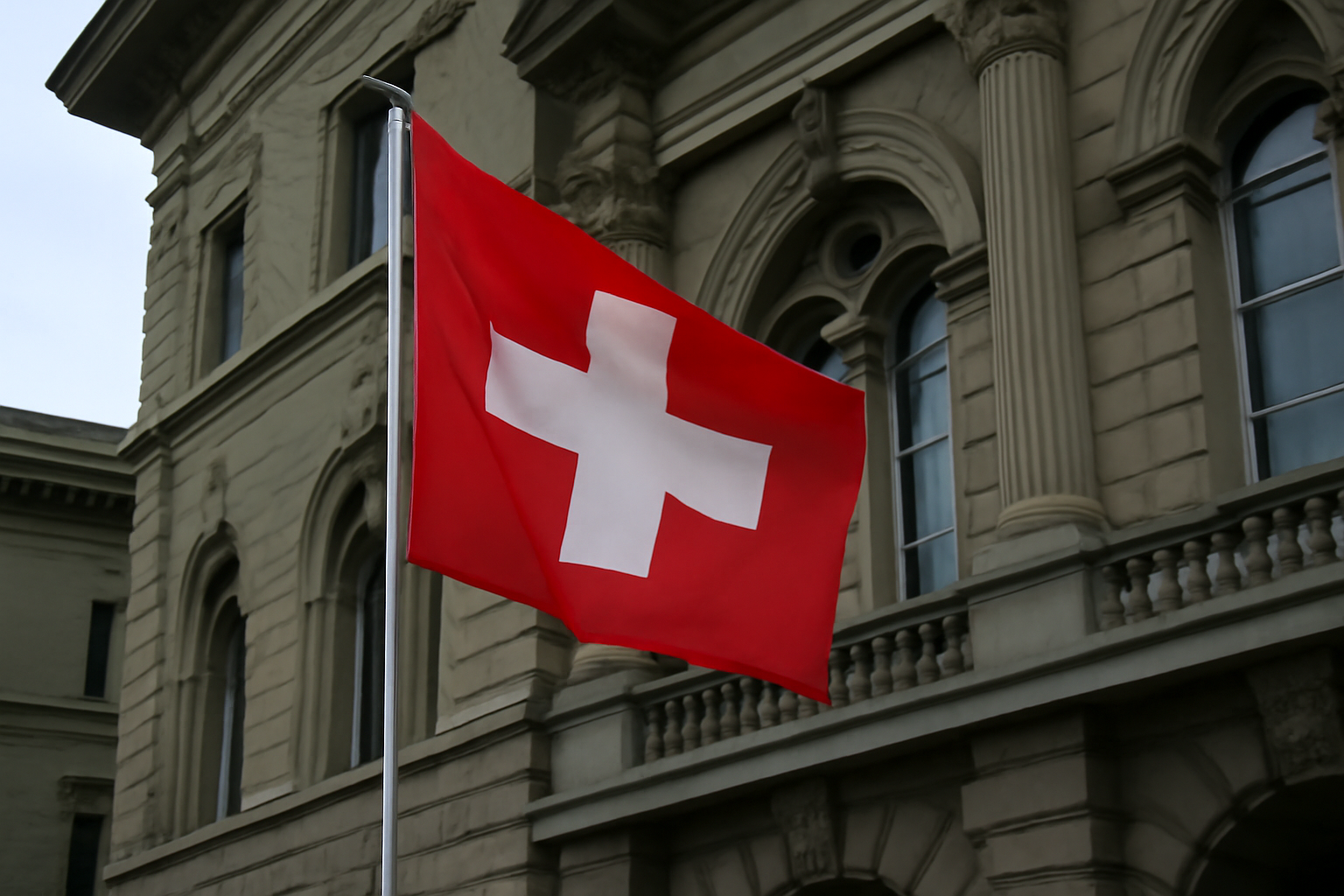 Swiss flag flying outside a government building under an overcast sky