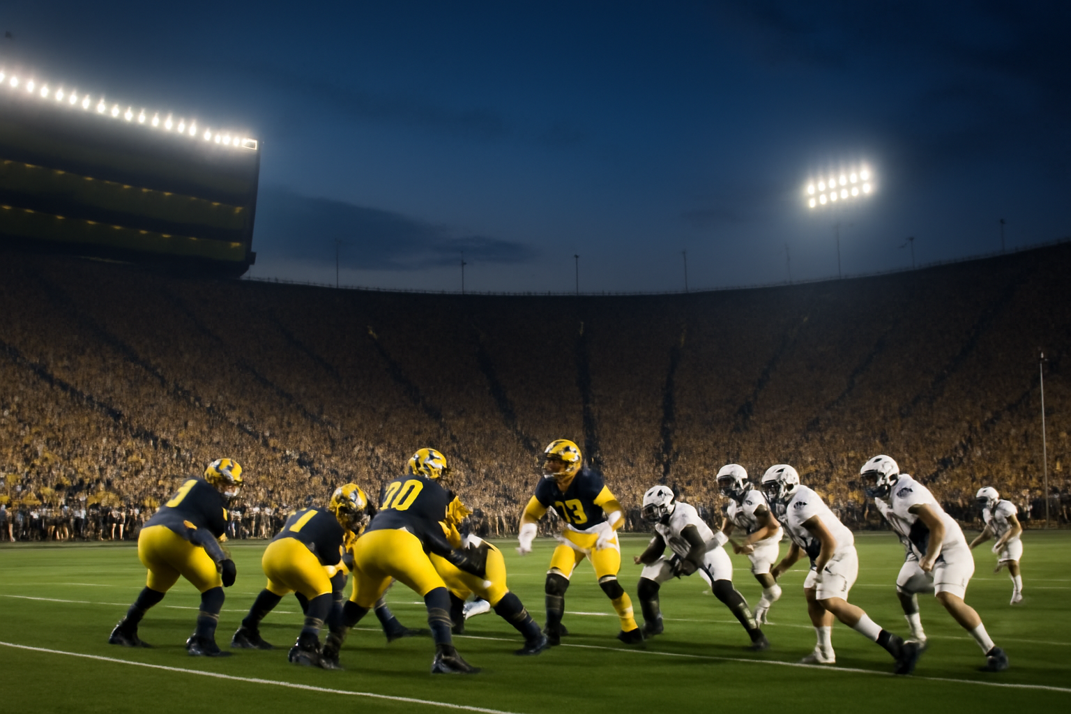 Michigan football players on the field at Michigan Stadium during a Big Ten night game against Penn State