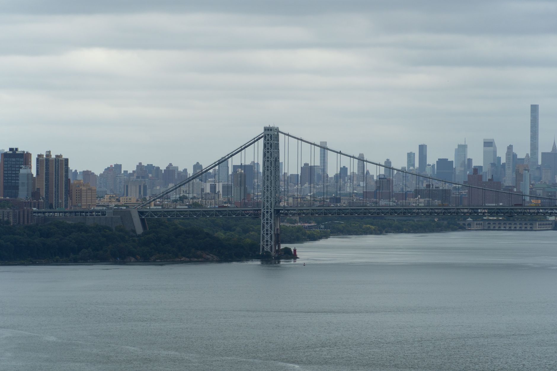 Traffic lanes on a suspension bridge's upper deck with a police patrol vehicle parked along the shoulder