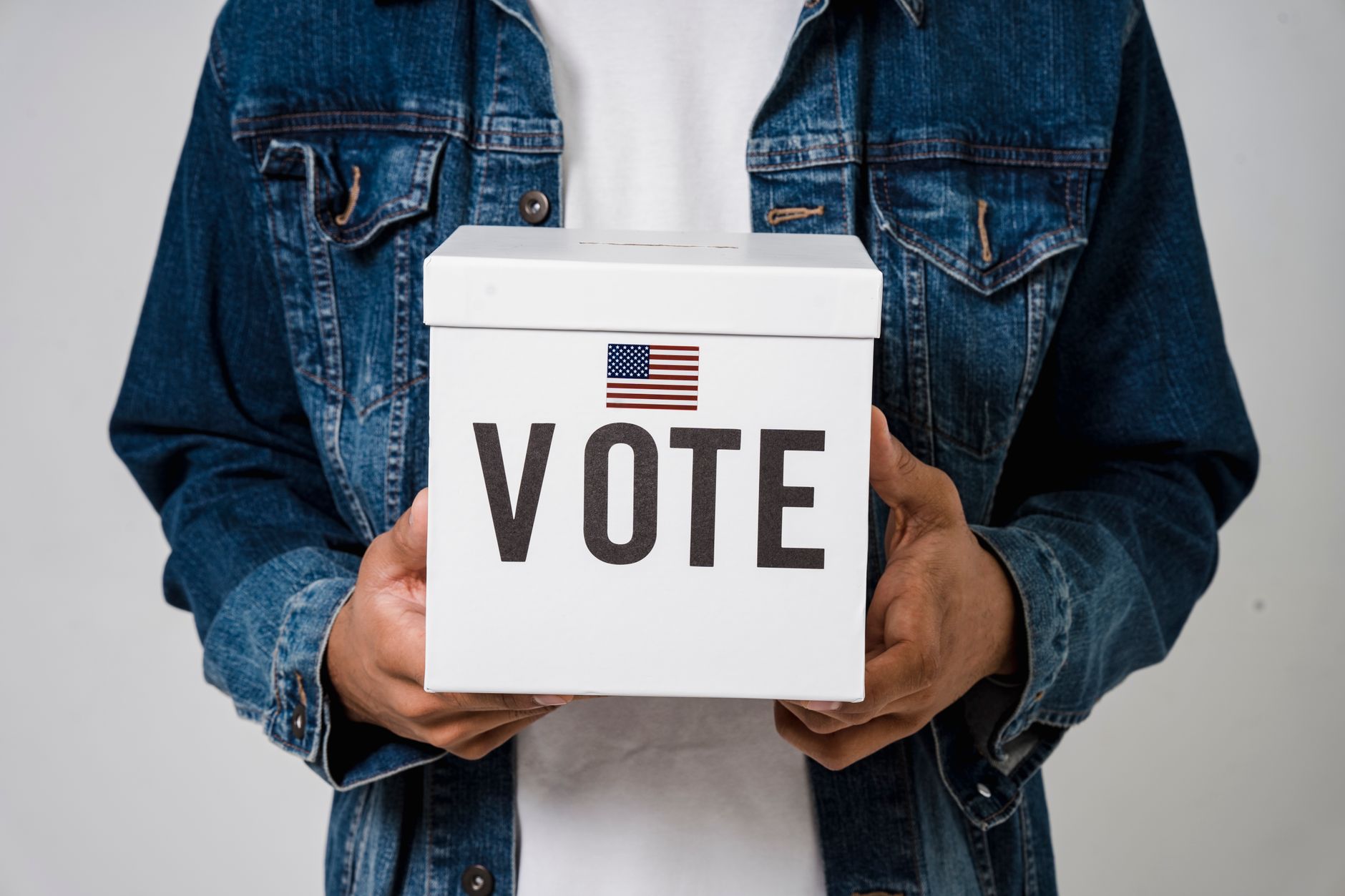 Voters dropping ballots into an election drop box outside a polling location