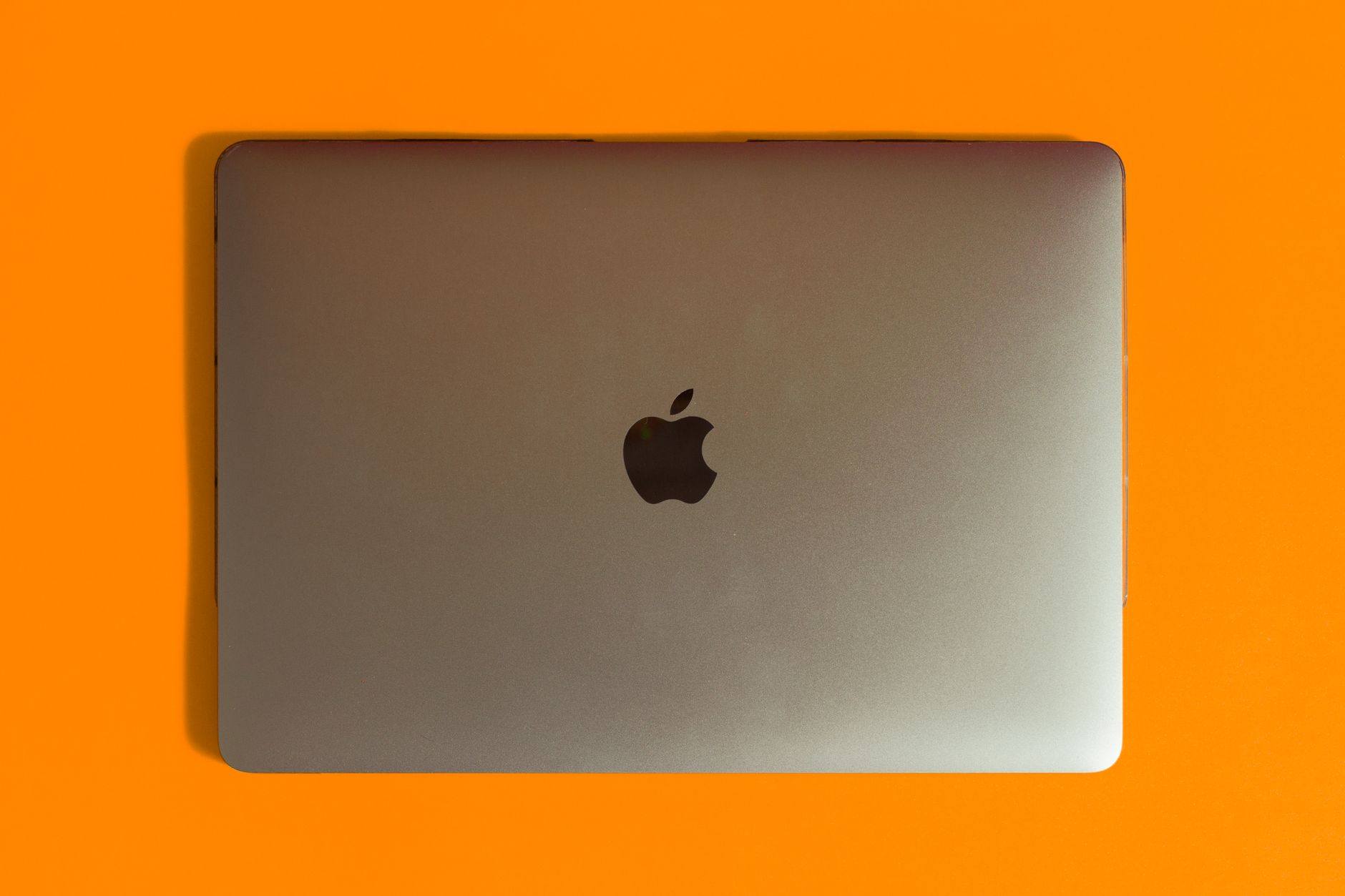 Close-up of a MacBook Pro keyboard deck and display hinge under studio lighting